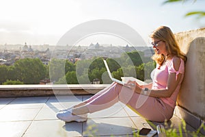 Woman working with laptop on terrace overlooking city