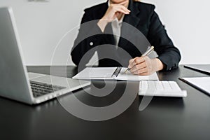 Business woman working in office writing plan on note book and use computer laptop to plan marketing strategy