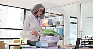 Business woman working in stacks of papers and looking for information about documents in stack of checks