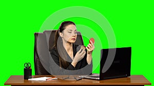 Business woman at workplace makes make-up and applying powder on face skin looking in a red mirror. Green screen