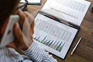 Business woman at workplace at wooden office table analyzes the data, schedules, prices, makes calculations on a calculator