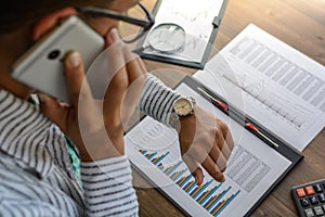 Business woman at workplace at wooden office table analyzes the data, schedules, prices, makes calculations on a calculator