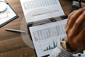 Business woman at workplace at wooden office table analyzes the data, schedules, prices, makes calculations on a calculator