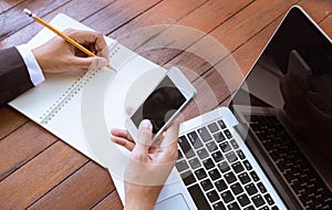 Business woman write on notebook and use cell phone working outdoor in coffee shop vintage tone