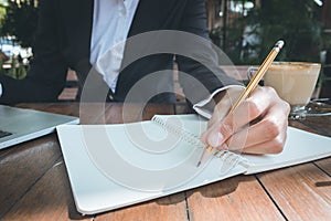 Business woman write on notebook and use laptop working outdoor in coffee shop vintage tone