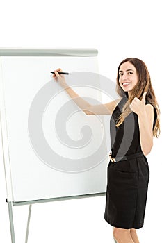 Business woman writing on a board and giving thumbs up