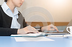 Business woman writing on calendar book and typing on laptop,