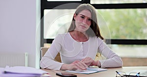 Business woman writing in notepad with pen and calculating financial statements in office