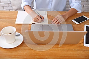 Business woman writing on paper with laptop and smarthpone