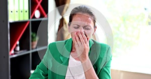 Business woman yawns at modern office desk at work