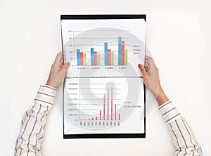 Business womans hands holding a folder with charts on a white table
