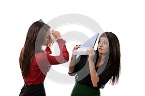 Business women beating each other with notebooks