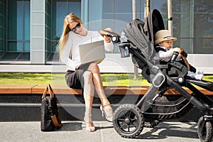 Business woman with child in stroller talking on the phone and working on laptop