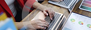 Business women colleagues are typing on laptop keyboard at table in office closeup