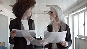Business women with documents standing and talking in office