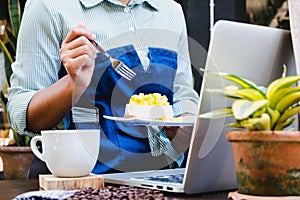 Business women eating cake after using laptop and drinking coffee