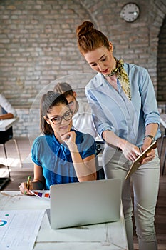 Business women entrepreneurs working in coworking space smiling, brainstorming as a team in office