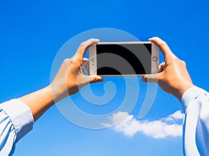 Business women hand holding smartphone on blue sky and clouds background for online searching
