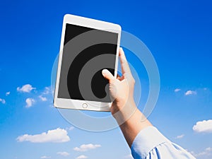 Business women hand holding tablet on blue sky and clouds background for online searching