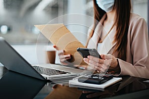 Business women hand working with smartphone and laptop computer with documents on office desk in modern office