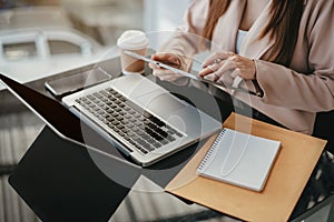 Business women hand working with tablet and laptop computer with documents on office desk