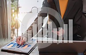 Business women hand working with tablet and laptop computer with documents on office desk in modern office