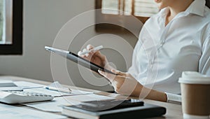 Business women hand working with tablet and laptop computer with documents on office desk in modern office