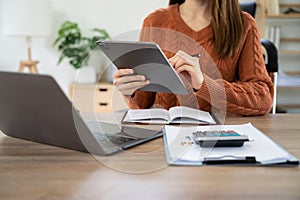 Business women hand working with tablet and laptop computer with documents on office desk in modern office