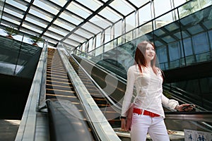 Business women holding mobile phone on escalator