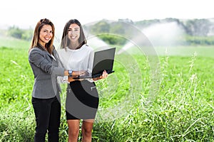 Business women with a laptop in a field with agriculture irrigation system