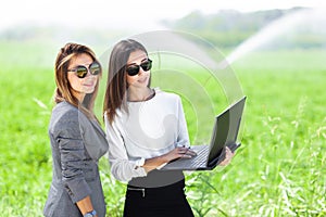 Business women with a laptop in a field with agriculture irrigation system