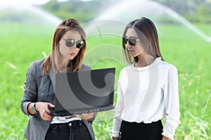 Business women with a laptop in a field with agriculture irrigation system