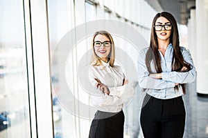 Business women in office hall over panoramic windows.