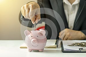 Business women put money coins into piglets to save money and financial.