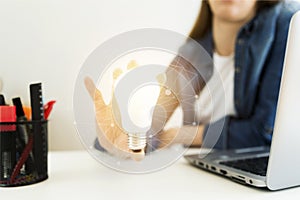 Business women`s, designer`s hand holding light bulb, concept of new ideas with innovation and creativity.