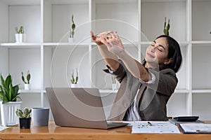 Business women stretch oneself or lazily for relaxation on her desk while doing her work in the office