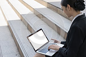 Business women typing word into laptop with blank white monitor