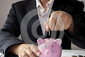 Business women who put coins in a piggy bank, the concept of saving money.