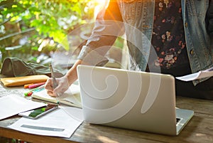 A business women is working on desk office with her computer laptop and writing accounts for investment. interior design of