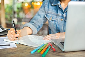 A business women is working on desk office with her computer laptop and writing accounts for investment. interior design of manage