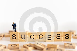 Business and work concept. Businessman miniature figure people standing with show thumb up on wooden letter block wording Success