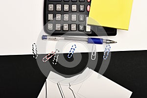 Business and work concept. Office tools on black and white background. Stationery and calculator, top view. Yellow note