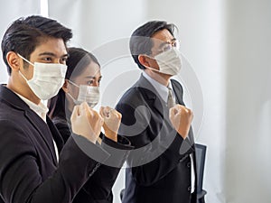 Business workers wear masks to protect and take care of their health.group asia business team is raising hands in fists stong