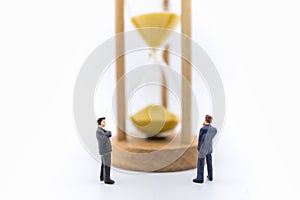 Business, Workin, Time and Management concept. Close up of two businessman miniature figure standing and looking to sandglass on