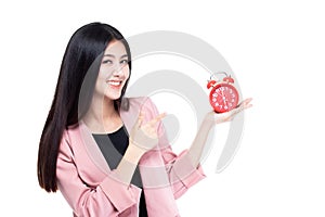 Business working time concept. Smiling asian business young woman holding clock and looking at camera isolated on white background