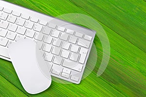 Business workplace with computer, wireless keyboard, keys and mouse on old green wooden table background. Office desk with copy