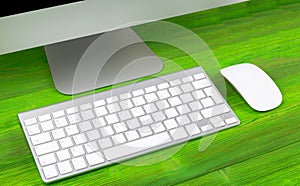 Business workplace with computer, wireless keyboard and mouse on old green wooden table background. Office desk with copy space