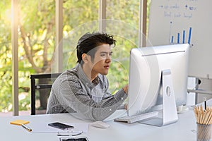 Business and workplace concept. Portrait of smart young asian businessman sitting working and looking to monitor of desktop