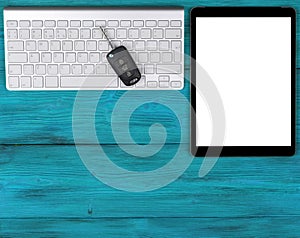 Business Workplace with wireless keyboard, tablet computer and car keys on blue wooden background. Office desk with copy space. Em