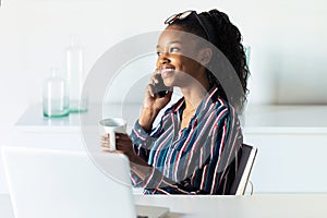 Business young woman talking on mobile phone while drinking coffee in the office